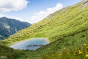 Le petit lac Lacroix : prairie verte et vue sur le vallon de Ségure